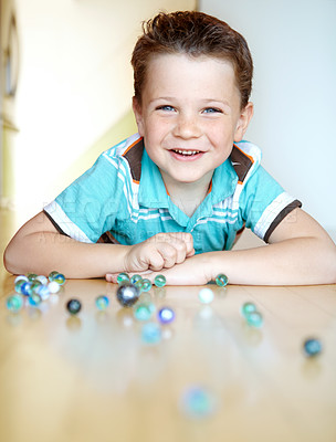 Buy stock photo Home, boy and happy with playing marbles on portrait for fun on school break on floor in Scotland. Male person, kid and happy at apartment with toys for games, child growth and brain development