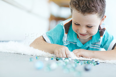 Buy stock photo Smile, child and boy play with marble on floor for game, relax and learning in home. Happy, kid and glass balls or toys on carpet for creative collection, education or childhood development in house