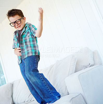 Buy stock photo Dancing, play or kid with air guitar on sofa for comedy, humour or funny joke for rock and roll. Happy, excited or crazy boy child with music, celebration or imaginary instrument on couch in home