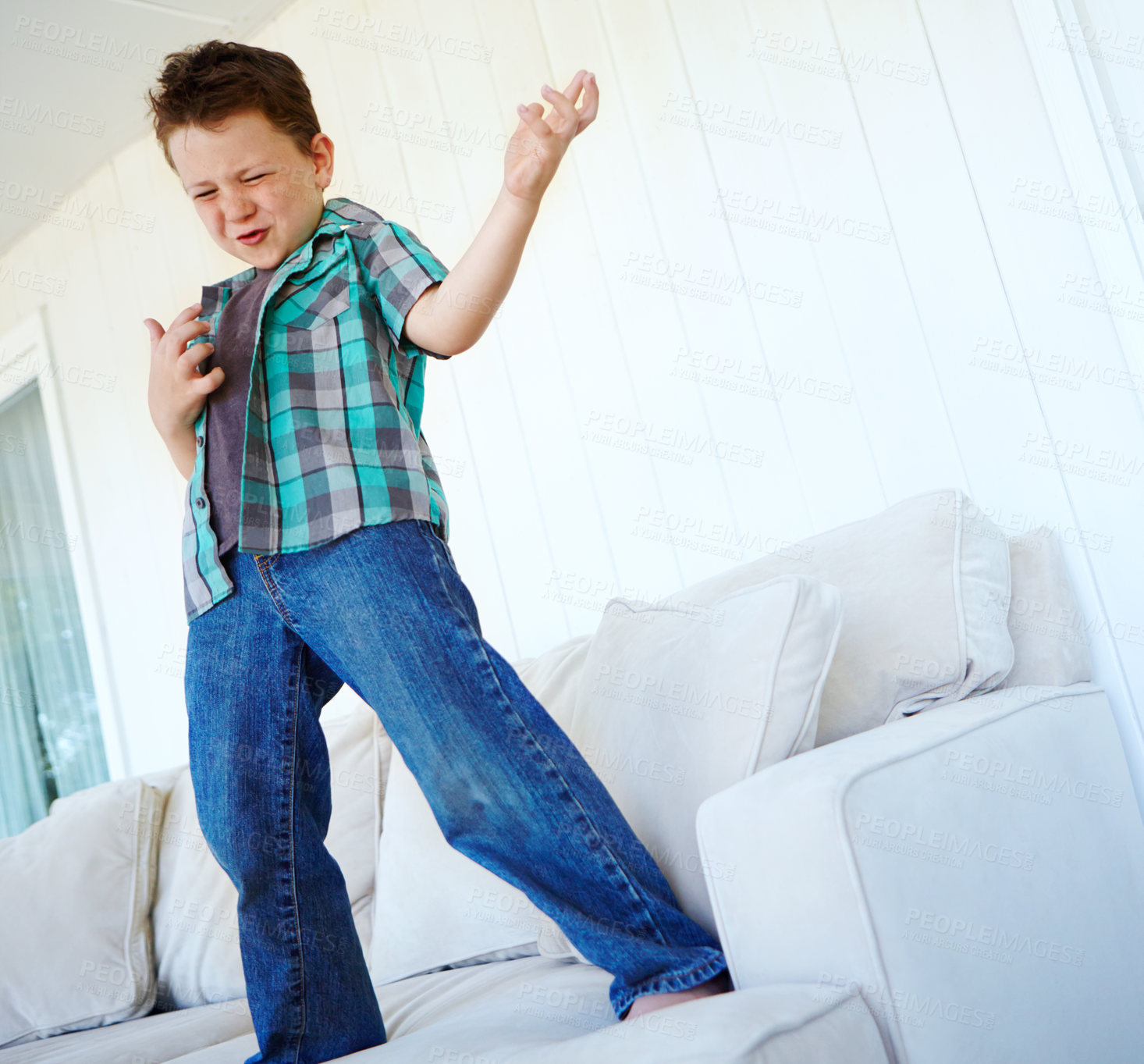 Buy stock photo Dancing, play or child with air guitar on sofa for comedy, humour or funny joke for rock and roll. Happy, excited kid or crazy boy with music, celebration or imaginary instrument on couch in home