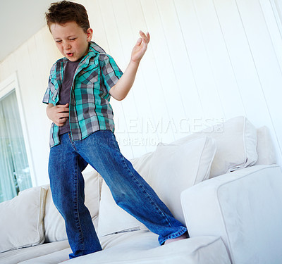 Buy stock photo Dancing, play or boy with air guitar on sofa for comedy, humour or funny joke for rock and roll. Happy, excited kid or crazy child with music, celebration or imaginary instrument on couch in home