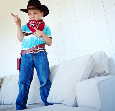 Buy stock photo Kid, cowboy and play game with gun gesture for fantasy and creative cosplay in home living room. Boy child, western costume and pistol fingers on sofa for shooting, pretend or dress up for halloween