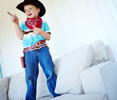 Buy stock photo Child, cowboy and play game with gun gesture for fantasy and creative cosplay in home living room. Kid boy, western costume and pistol fingers on sofa for shooting, pretend or dress up for halloween