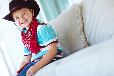 Buy stock photo Cowboy, costume and portrait of child on sofa with smile for cosplay, character outfit and cartoon. Happy, relax and boy with hat excited for Halloween party, trick or treat and scarf in living room