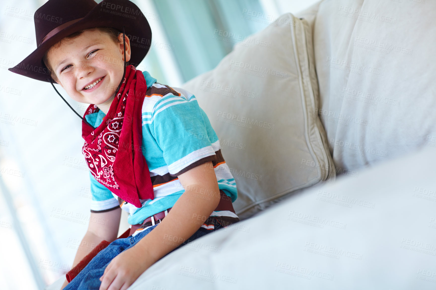 Buy stock photo Cowboy, costume and portrait of child on sofa with smile for cosplay, character outfit and cartoon. Happy, relax and boy with hat excited for Halloween party, trick or treat and scarf in living room