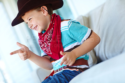 Buy stock photo Happy kid, cowboy and play game with gun gesture for fantasy or creative cosplay in home lounge. Boy child, western costume and pistol fingers on sofa for shooting, target or dress up for halloween