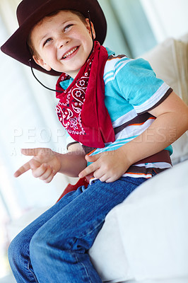 Buy stock photo Kid, boy and happy with cowboy costume on sofa for fantasy play, shooting game and pointing pretend gun. Person, smile and hand gesture in home for halloween, dress up and protection with imagination