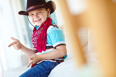 Buy stock photo Child, boy and portrait with cowboy costume in home for fantasy play, shoot game and pointing pretend gun. Person, smile or hand gesture on sofa for halloween, dress up or protection with imagination