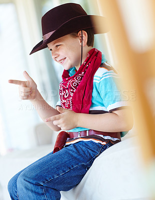 Buy stock photo Kid, boy and smile with cowboy costume in home for fantasy play, shooting game and pointing pretend gun. Person, happy and hand gesture on sofa for halloween, dress up and protection with imagination