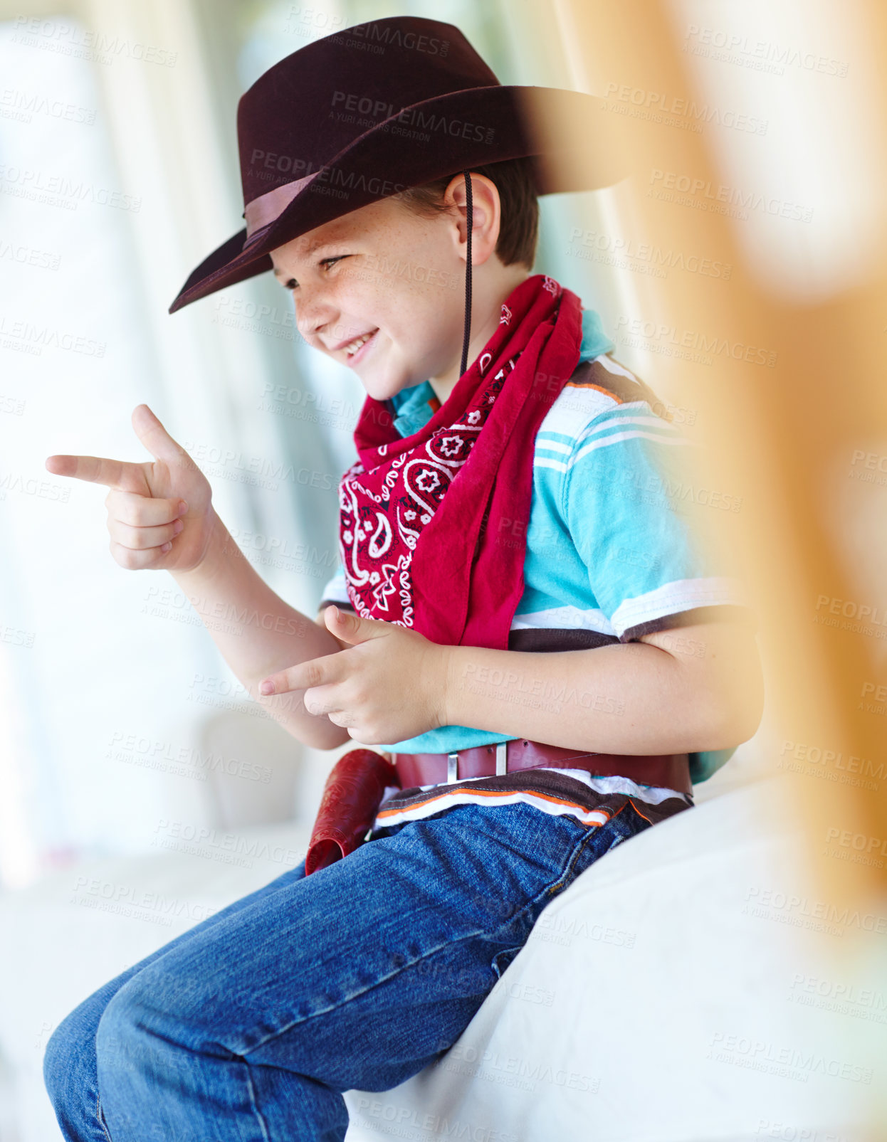 Buy stock photo Kid, boy and smile with cowboy costume in home for fantasy play, shooting game and pointing pretend gun. Person, happy and hand gesture on sofa for halloween, dress up and protection with imagination