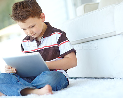 Buy stock photo Child, tablet and relax on floor in home, reading ebook and watch cartoon in living room. Boy, kid and digital technology for internet addiction, scroll app and playing game for education on carpet