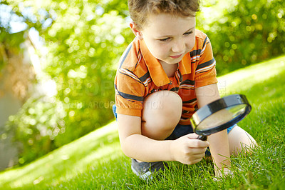 Buy stock photo Outdoor, boy and grass with magnifying glass for check, observe ecology and learning nature with smile. Backyard, child and curiosity with tool for discovery, studying biology and plants knowledge