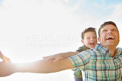 Buy stock photo A cute little boy being piggybacked by his father on a sunny day