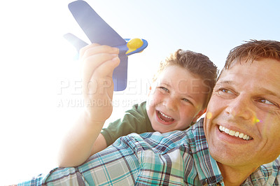 Buy stock photo A cute little boy playing with an airplane while being carried on his father's back