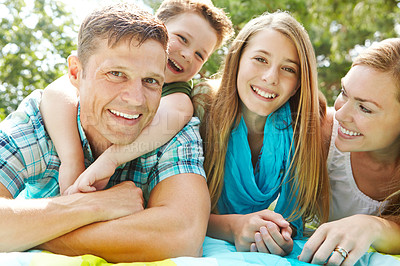 Buy stock photo A happy young family lying on the ground together at the park