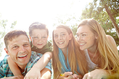 Buy stock photo A happy young family lying on the ground together at the park