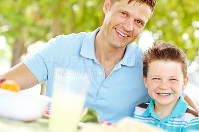 Buy stock photo A happy father sitting at a picnic table with his young son on a summer's day