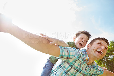 Buy stock photo A cute little boy being piggybacked by his father on a sunny day