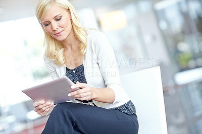 Buy stock photo A business woman looking at her digital tablet in an office environment with copyspace