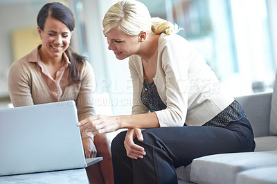 Buy stock photo Shot of two business colleagues looking at a laptop and smiling