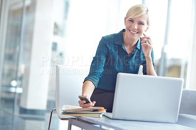 Buy stock photo Portrait of a smiling business woman sitting behind her laptop checking her phone with copyspace
