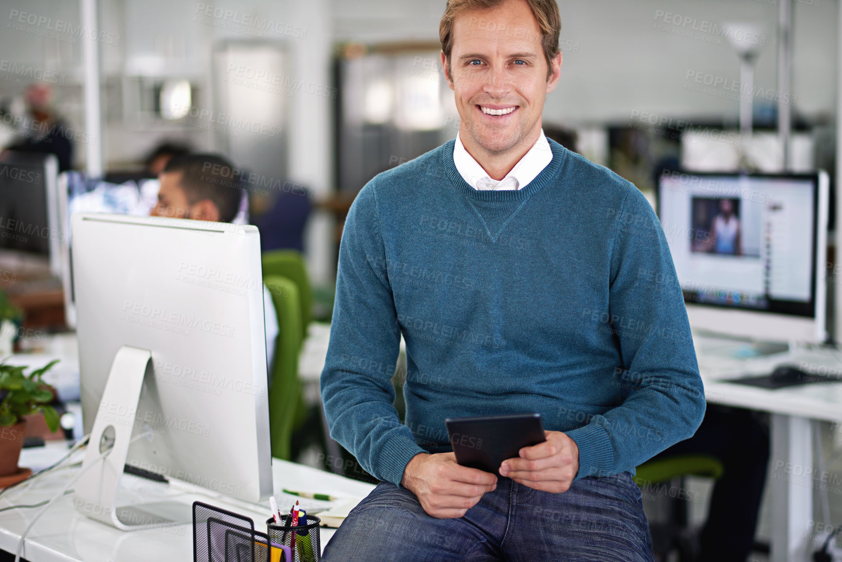 Buy stock photo Sitting man and confident with smile by computer for video editing, working with content. Male employee and tablet with cheer in office for digital, technology or online at table with colleague