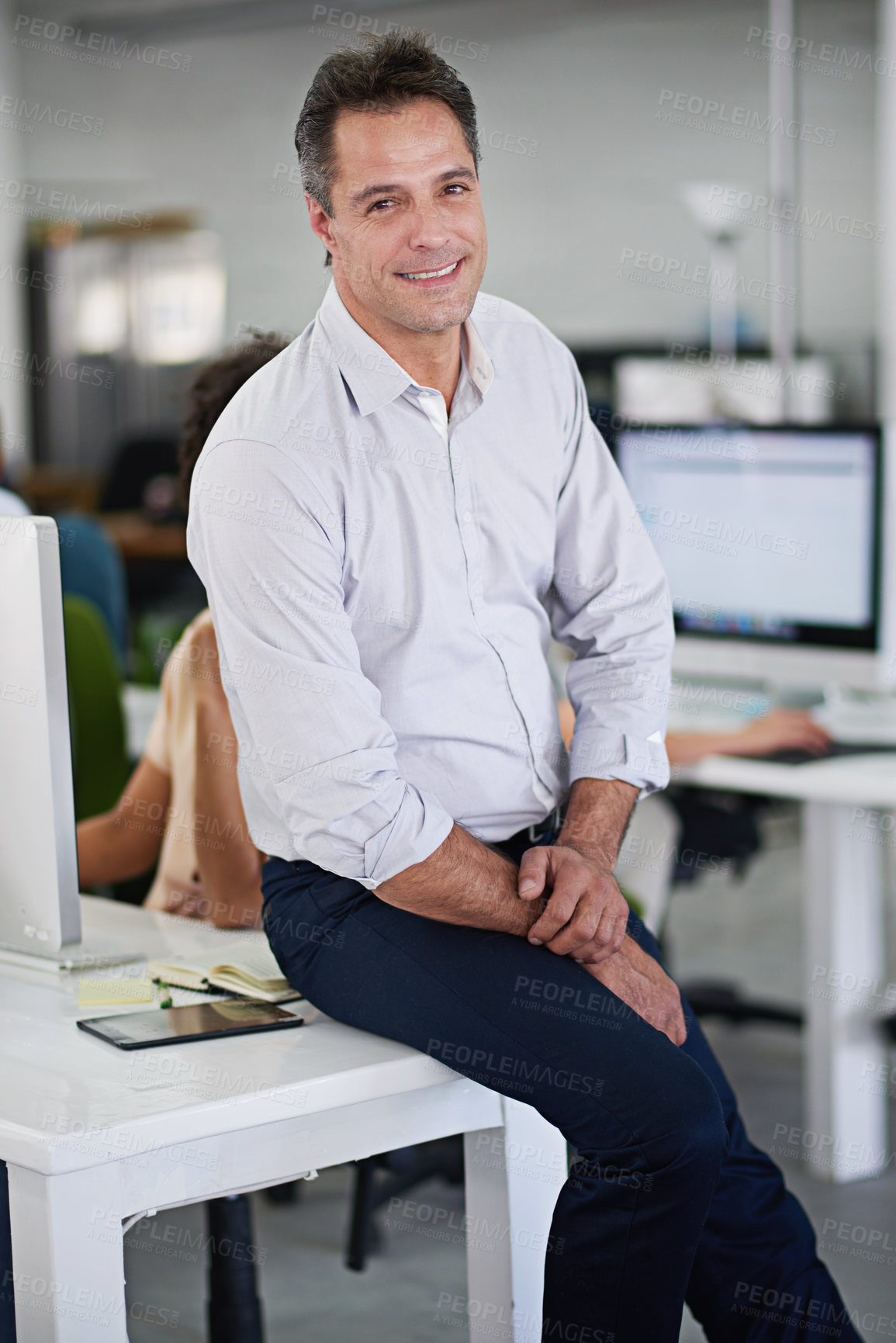 Buy stock photo Businessman, smile and portrait on desk in office with tablet, colleagues and workplace. Project, manager and male person in company for work, career and corporate with technology and notebook