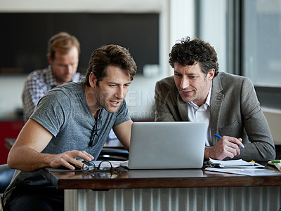 Buy stock photo Shot of two male colleagues talking together over a laptop