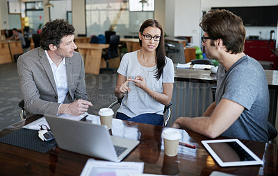 Buy stock photo Shot of three coworkers talking together in an office