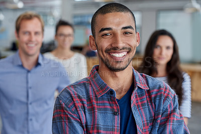 Buy stock photo Young smiling man with coworkers behind him