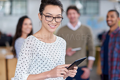 Buy stock photo Friendly young woman holding a digital tablet with smiling staff behind her