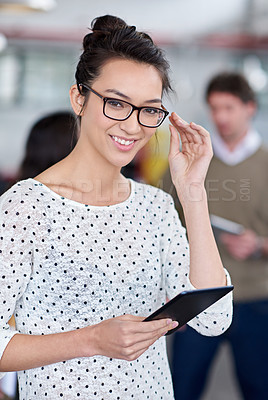 Buy stock photo Intelligent young woman smiling at the camera while holding a digital tablet