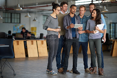 Buy stock photo Group of colleagues having an impromptu meeting in an open office using a digital tablet