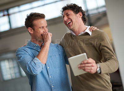 Buy stock photo Two guy friends laughing about something funny they've just seen on a digital tablet