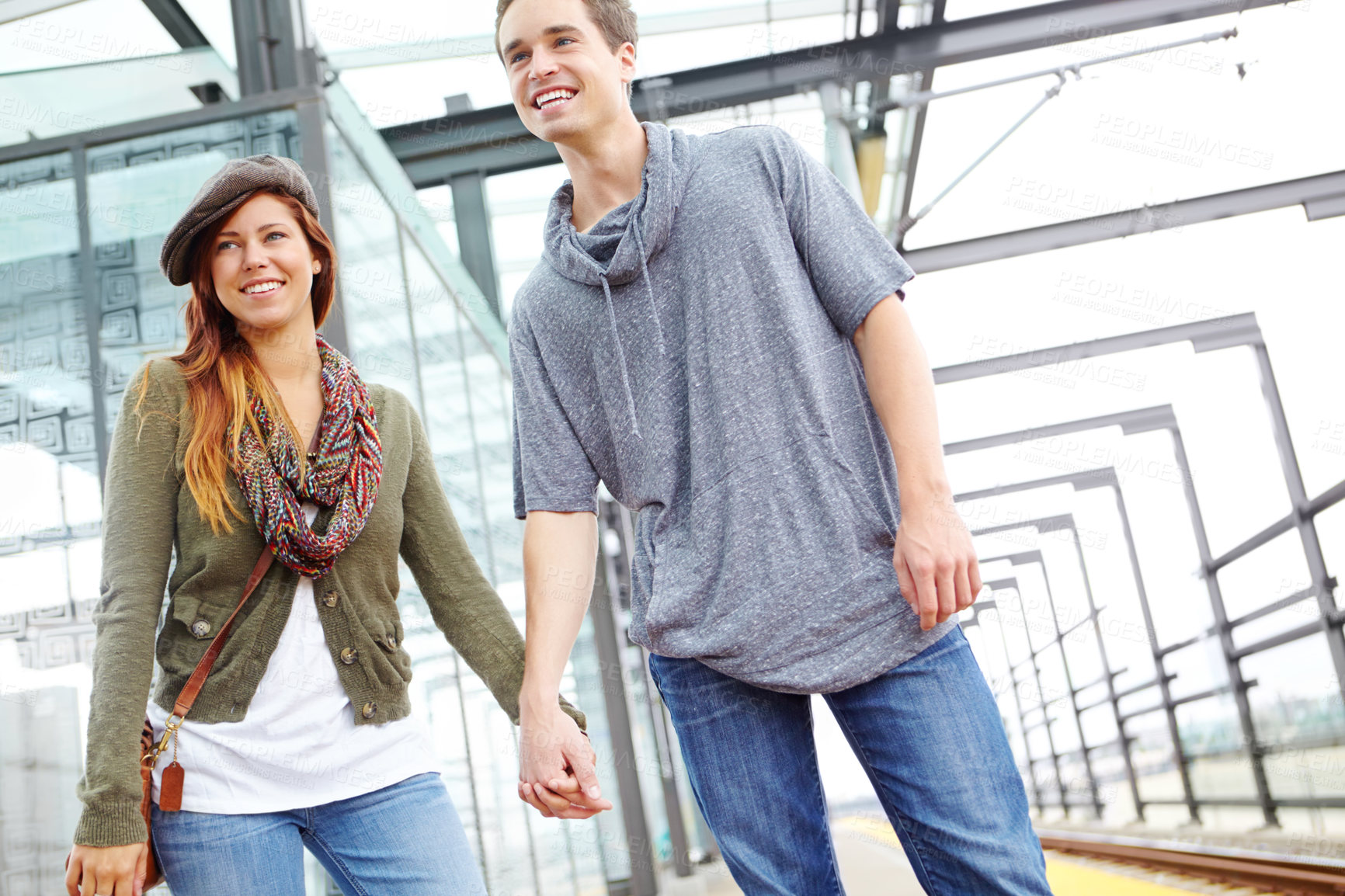 Buy stock photo Happy couple, travel or holding hands with railway at train station for rail trip, holiday or vacation in city. Young, man and woman with smile, romance or support for love, date or tour around town