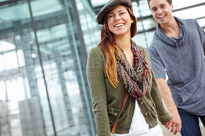 Buy stock photo Portrait of a happy woman holding her boyfriend's hand while walking in a train station with copyspace
