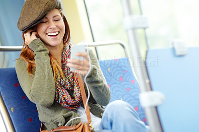 Buy stock photo Pretty girl laughing on a train listening to her music on her phone with copyspace