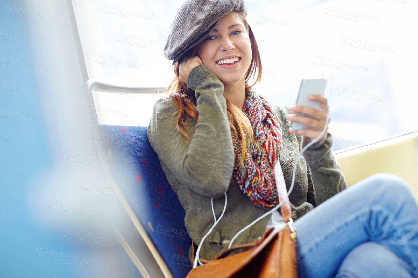 Buy stock photo Portrait of a pretty girl on a train listening to her music on her phone with copyspace