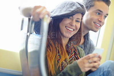 Buy stock photo Shot of a happy couple on the train with the girlfriend texting on her cellphone