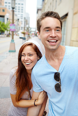 Buy stock photo A happy couple holding hands and walking along a city street 