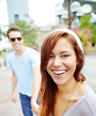 Buy stock photo Portrait of a beautiful happy woman holding hands with her boyfriend on a city street