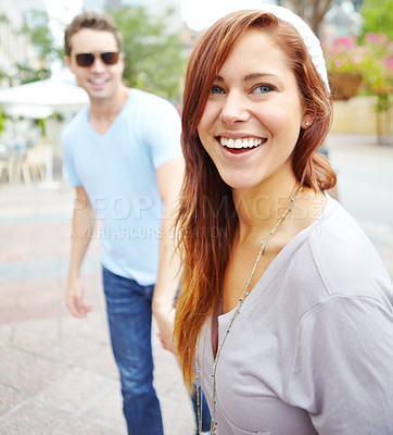 Buy stock photo Portrait of a beautiful happy woman holding hands with her boyfriend on a city street