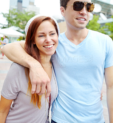 Buy stock photo A couple with their arms around each other walking outside