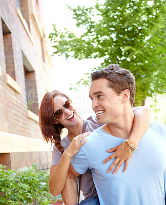 Buy stock photo A happy girlfriend getting a piggyback from her boyfriend