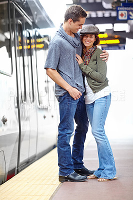 Buy stock photo A happy couple hugging each other at a train station