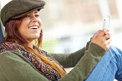 Buy stock photo Shot of a beautiful woman waiting at a train station and listening to music on her cellphone