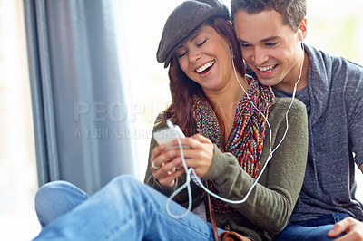 Buy stock photo A close couple listening to music together on a phone and laughing together