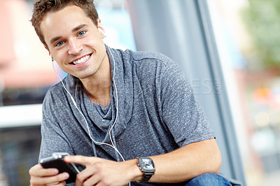 Buy stock photo Portrait of a handsome young man listening to music on his phone
