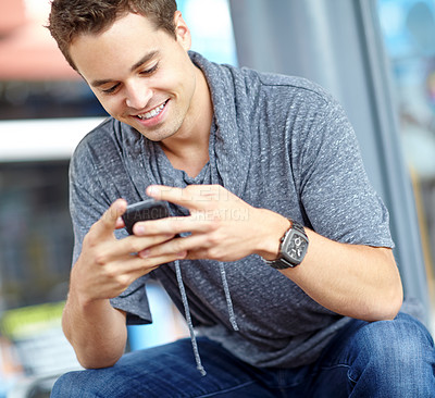 Buy stock photo A good looking young man typing on his cell phone