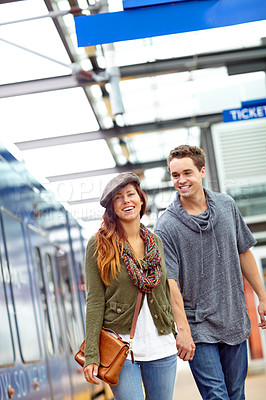 Buy stock photo A good looking couple holding hands while walking in a train station with copyspace